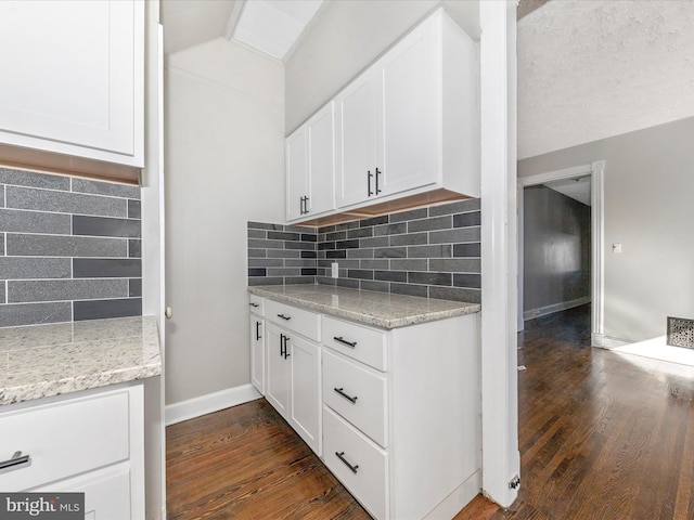 kitchen featuring white cabinetry, dark wood-type flooring, backsplash, and light stone counters