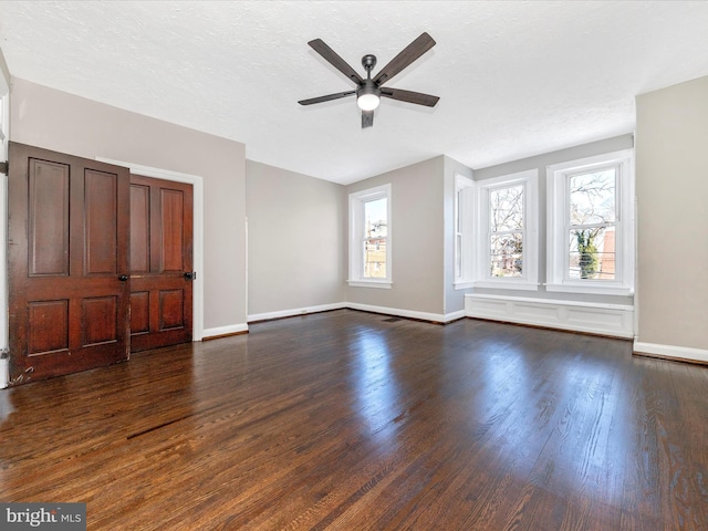 unfurnished living room featuring dark hardwood / wood-style flooring, a textured ceiling, and a healthy amount of sunlight