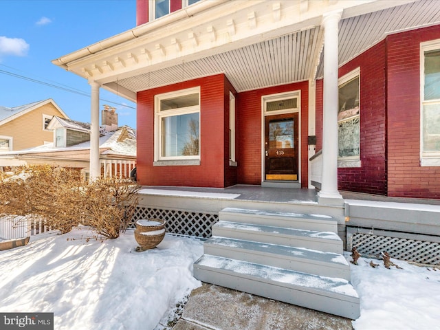 snow covered property entrance with a porch