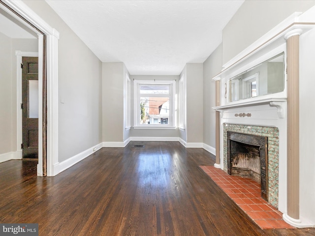 unfurnished living room with a tile fireplace and dark hardwood / wood-style floors