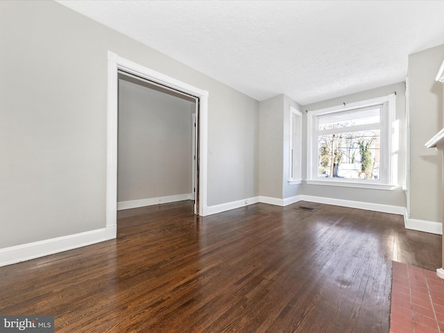 unfurnished living room featuring a textured ceiling and dark hardwood / wood-style flooring