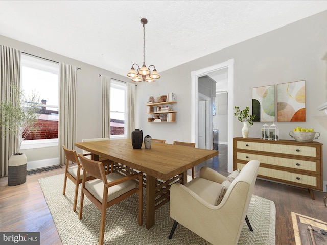 dining space featuring dark wood-type flooring, an inviting chandelier, and a textured ceiling