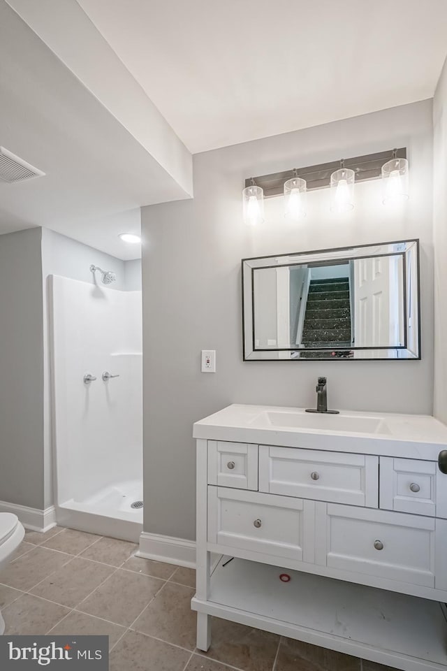 bathroom featuring toilet, tile patterned floors, walk in shower, and vanity