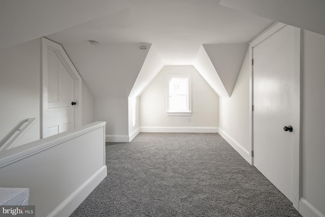 bonus room with lofted ceiling and dark carpet