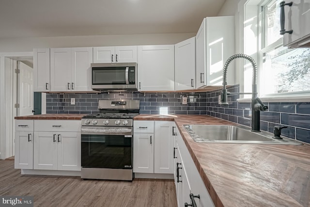 kitchen with white cabinets, wooden counters, and appliances with stainless steel finishes