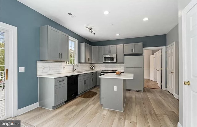 kitchen featuring stainless steel appliances, decorative backsplash, a center island, and gray cabinetry