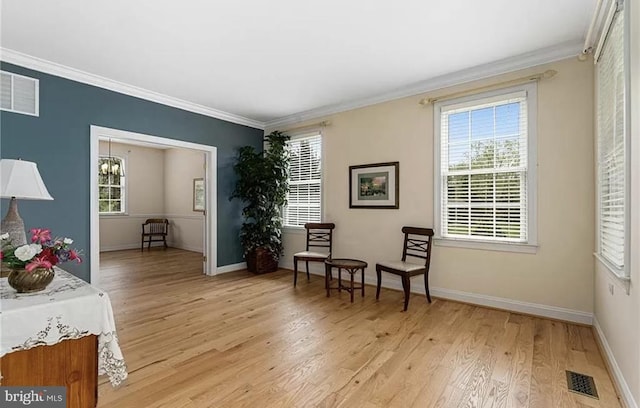 living area featuring an inviting chandelier, light hardwood / wood-style floors, and crown molding