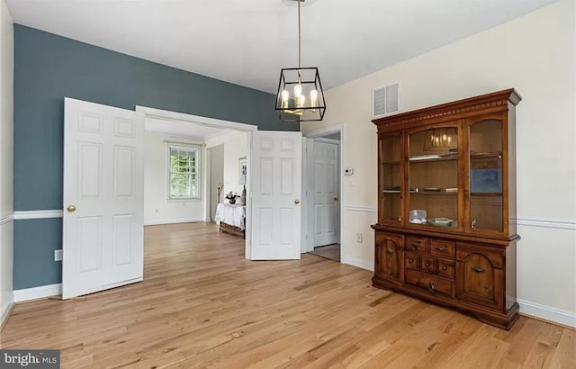 unfurnished dining area with a notable chandelier and light hardwood / wood-style floors