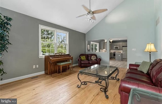 living room with high vaulted ceiling, ceiling fan, and light wood-type flooring