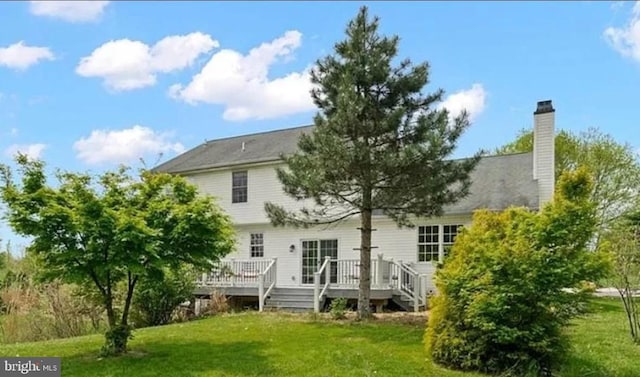 back of property featuring a deck and a yard