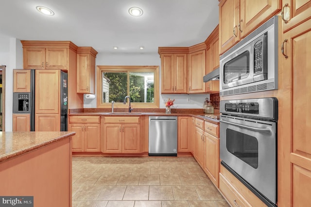 kitchen featuring light brown cabinetry, sink, appliances with stainless steel finishes, and range hood