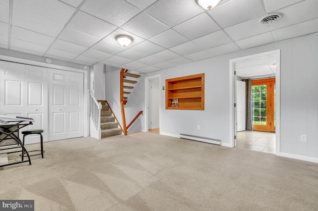 basement featuring baseboard heating, light carpet, and a drop ceiling