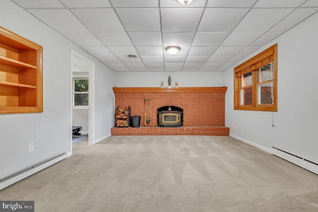 unfurnished living room with a paneled ceiling, a wood stove, a baseboard heating unit, and built in features