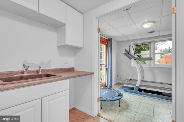 kitchen featuring light tile patterned floors, sink, white cabinets, and a paneled ceiling