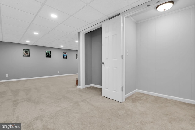 basement featuring a drop ceiling and light colored carpet