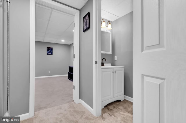 interior space featuring light colored carpet, a drop ceiling, and sink