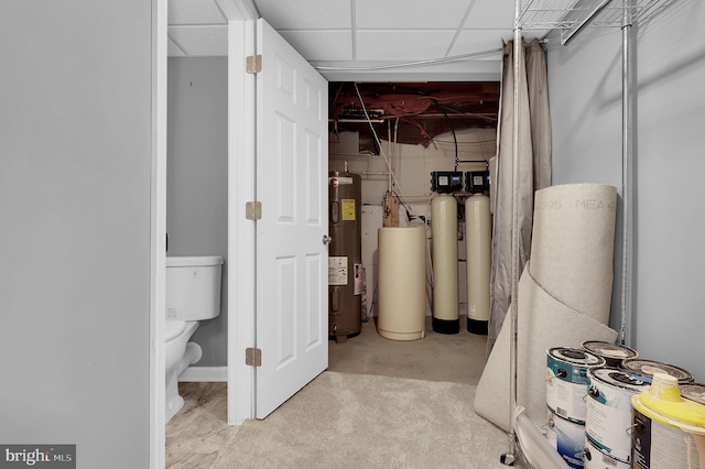 basement with a paneled ceiling and water heater