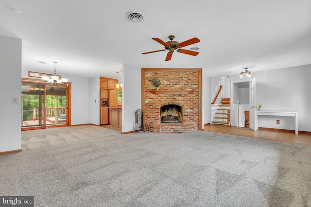 unfurnished living room with a fireplace, ceiling fan with notable chandelier, and light colored carpet