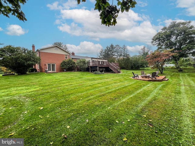 view of yard featuring a deck and a fire pit