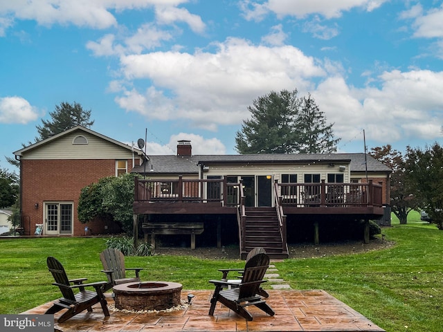 rear view of property featuring a patio, a lawn, a wooden deck, and a fire pit