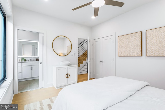 bedroom featuring ceiling fan, light hardwood / wood-style flooring, connected bathroom, and a closet