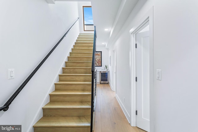 staircase with wood-type flooring and beverage cooler