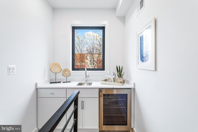 bar featuring white cabinets, beverage cooler, and sink