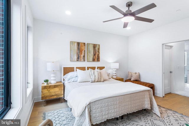 bedroom with ensuite bath, ceiling fan, and light hardwood / wood-style floors