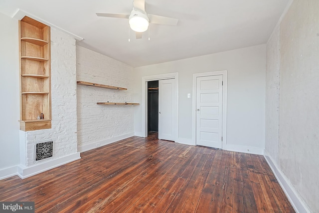 unfurnished bedroom featuring ceiling fan, dark hardwood / wood-style floors, and a stone fireplace