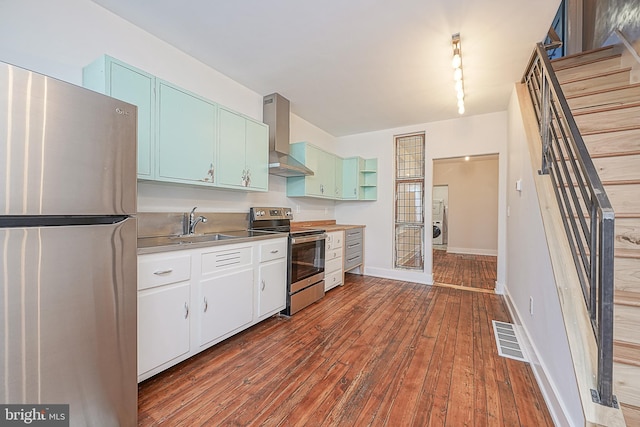 kitchen with hardwood / wood-style floors, track lighting, wall chimney exhaust hood, white cabinetry, and stainless steel appliances