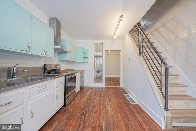 kitchen featuring white cabinetry, stainless steel electric range oven, dark hardwood / wood-style floors, wall chimney range hood, and sink