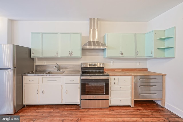 kitchen with hardwood / wood-style flooring, appliances with stainless steel finishes, stainless steel counters, wall chimney range hood, and sink