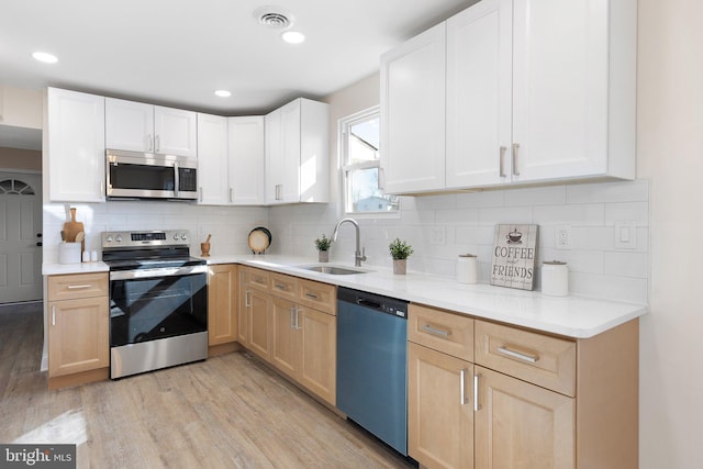 kitchen featuring sink, light hardwood / wood-style floors, tasteful backsplash, appliances with stainless steel finishes, and light brown cabinets