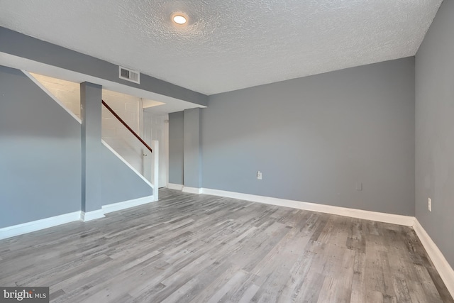 unfurnished room with a textured ceiling and light wood-type flooring