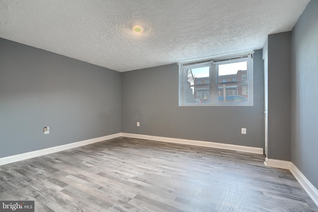 spare room featuring a textured ceiling and light hardwood / wood-style floors