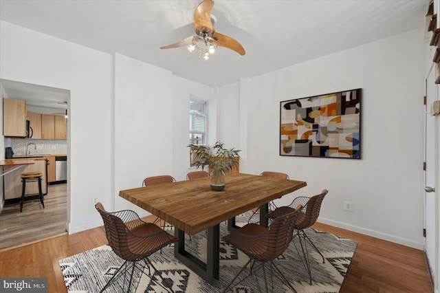 dining space with ceiling fan, sink, and light hardwood / wood-style flooring