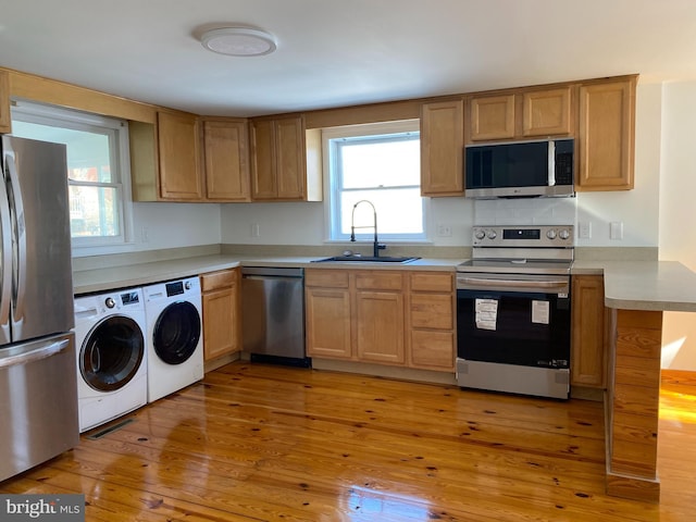 kitchen featuring a wealth of natural light, stainless steel appliances, light hardwood / wood-style floors, sink, and independent washer and dryer