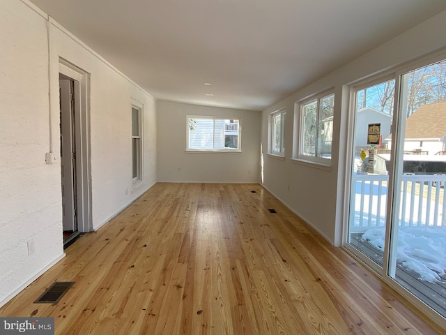 empty room featuring light hardwood / wood-style flooring and vaulted ceiling