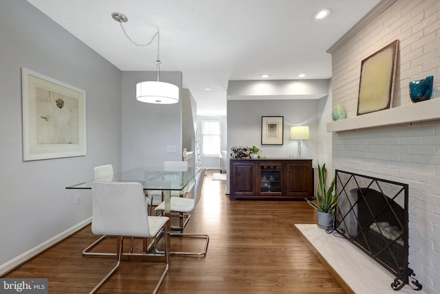 dining area featuring a brick fireplace, dark wood-style flooring, baseboards, and recessed lighting