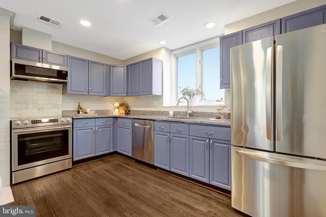 kitchen with stainless steel appliances, visible vents, a sink, and light stone countertops