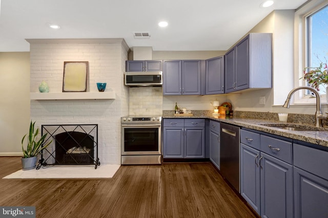 kitchen with dark wood finished floors, visible vents, appliances with stainless steel finishes, a sink, and dark stone countertops