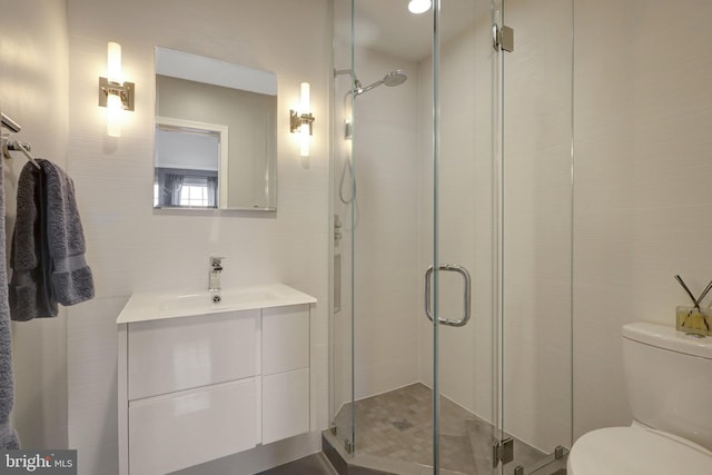 bathroom featuring toilet, a shower stall, and vanity