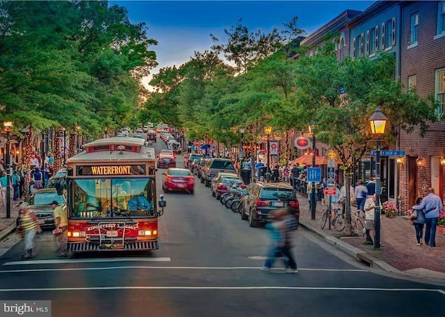 view of road featuring street lights, curbs, traffic signs, and sidewalks