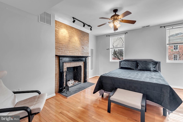 bedroom with visible vents, a fireplace, and light wood-type flooring