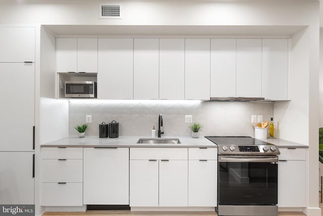 kitchen featuring sink, stainless steel appliances, white cabinets, and backsplash