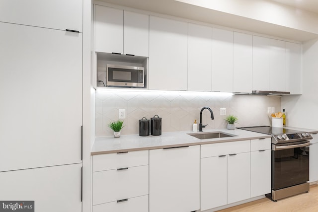 kitchen featuring white cabinets, appliances with stainless steel finishes, light hardwood / wood-style floors, and sink