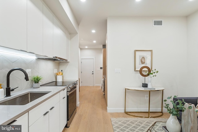 kitchen with stainless steel electric range oven, white cabinets, tasteful backsplash, and sink