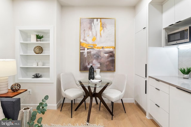 dining room with built in shelves and light hardwood / wood-style floors