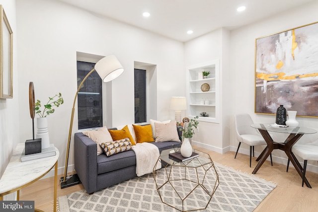 living area with built in features and light hardwood / wood-style flooring