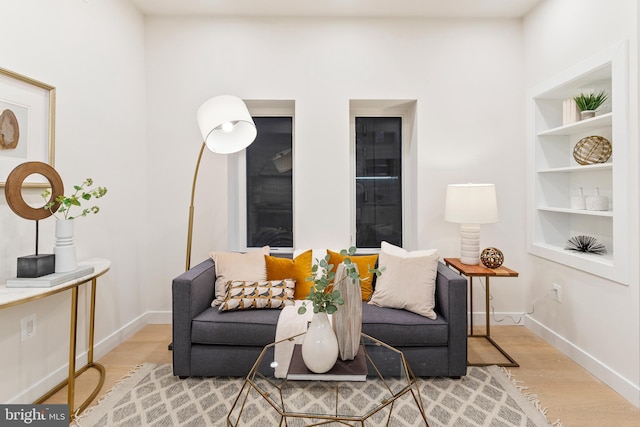 sitting room with wood-type flooring and built in features